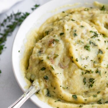 These Dairy Free Roasted Garlic Mashed Potatoes are a healthy vegan mashed potato recipe packed with flavor. They are a great plant-based holiday side dish or cozy everyday dinner side. Instead of butter, they use a creamy roasted garlic sauce made with silken tofu that adds extra protein without a ton of fat!