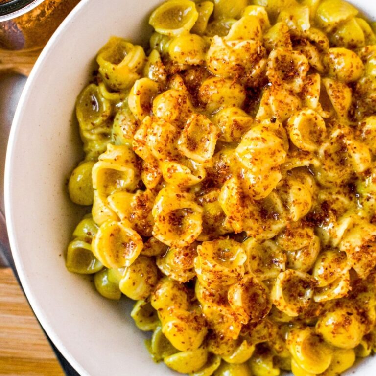 Overhead close up view of a round white bowl filled with a daiya mac and cheese recipe topped with coconut bacon salt