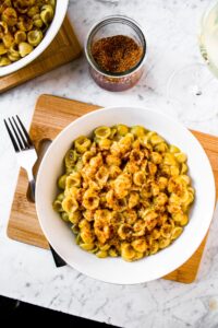 Overhead view of a round white bowl filled with a daiya mac and cheese recipe topped with vegan bacon