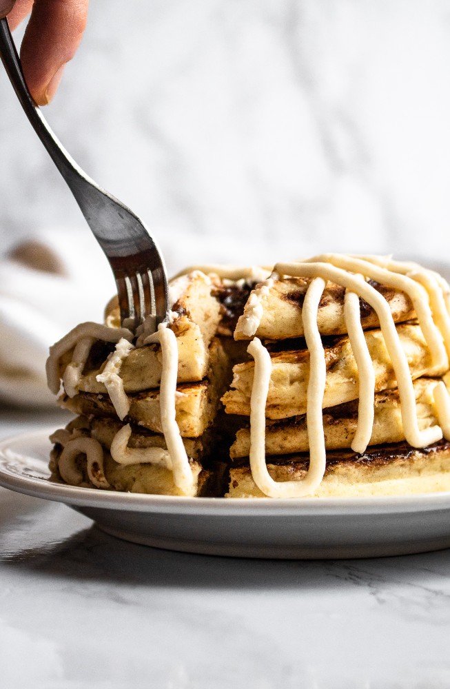These vegan cinnamon roll pancakes are a deliciously indulgent dairy-free breakfast! They are fluffy pancakes with a coconut sugar + cinnamon swirl, topped with a decadent cream cheese frosting. #vegan #veganpancakes #cinnamonroll #cinnamon #veganbreakfast #pancakes #plantpowercouple #dairyfree // plantpowercouple.com