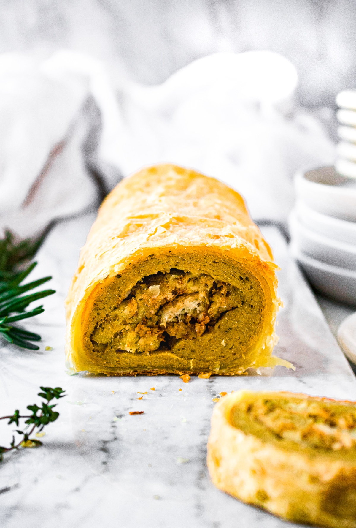 Head-on shot of a homemade vegan seitan roast with traditional bread stuffing wrapped in a puff pastry crust.