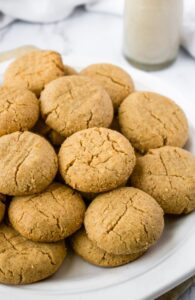 Head on photo of a pile of peanut butter cookies with the classic criss cross marks on a round white plate