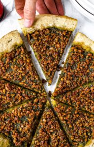 This quick no-proof vegan sausage and pesto pizza will prove itself with flavor time and again. Vegan pesto pizza is packed with dairy-free basil pesto sauce and wall-to-wall sausage-style walnut meat. The rustic whole wheat vegan pizza dough is easy to make, self-rising, and beer-based (which gives the crust its rich flavor). This healthy vegetarian pizza recipe can be made in under 40 minutes - less than the time it would take a yeasted dough to rise in its first proof!