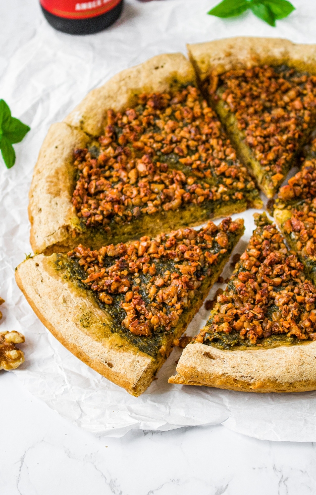 This quick no-proof vegan sausage and pesto pizza will prove itself with flavor time and again. Vegan pesto pizza is packed with dairy-free basil pesto sauce and wall-to-wall sausage-style walnut meat. The rustic whole wheat vegan pizza dough is easy to make, self-rising, and beer-based (which gives the crust its rich flavor). This healthy vegetarian pizza recipe can be made in under 40 minutes - less than the time it would take a yeasted dough to rise in its first proof!