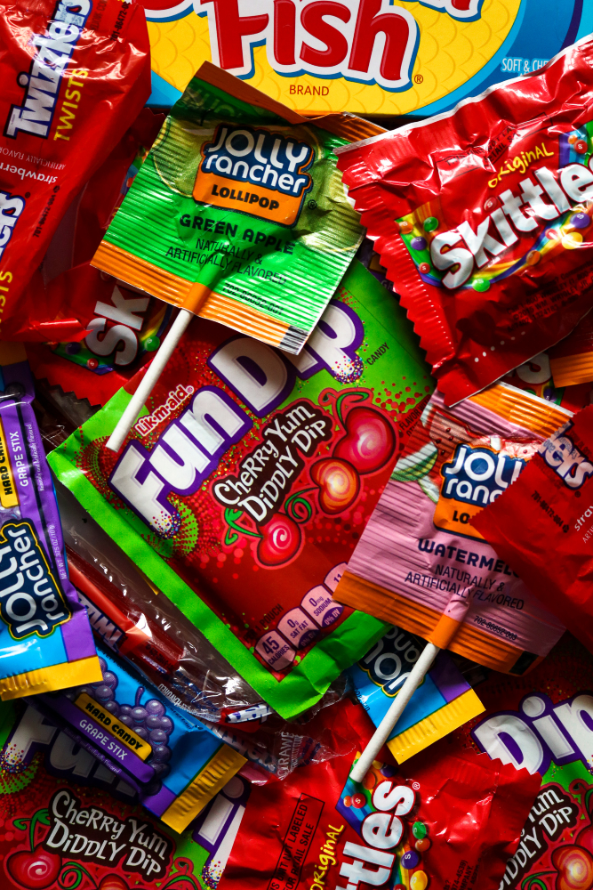 Overhead shot of a pile of vegan candy like Fun Dip, Skittles, and Jolly Rancher Lollipops