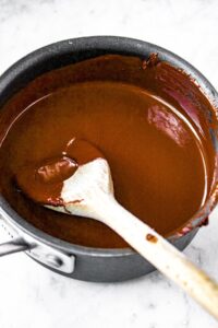 Overhead shot of a pot of melted chocolate with a wooden spoon stirring it