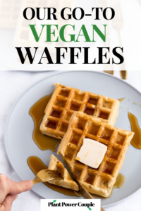 Overhead shot of two waffles piled on a large grey plate with a square of dairy free butter on top drenched in maple syrup. Two hands - one with a fork and one with a knife are shown cutting a corner of the waffle off. Text reads: our go-to vegan waffles