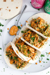 Tender, meaty shredded jackfruit slow-cooked in a spicy/sweet flavor bath, wrapped in a pollow-y tortilla, topped with a crisp sprinkle of kimchi, and smothered in a creamy cashew Gochujang sauce. These are Korean Jackfruit Tacos! #vegan #dinner #plantbased #jackfruit #tacos // plantpowercouple.com