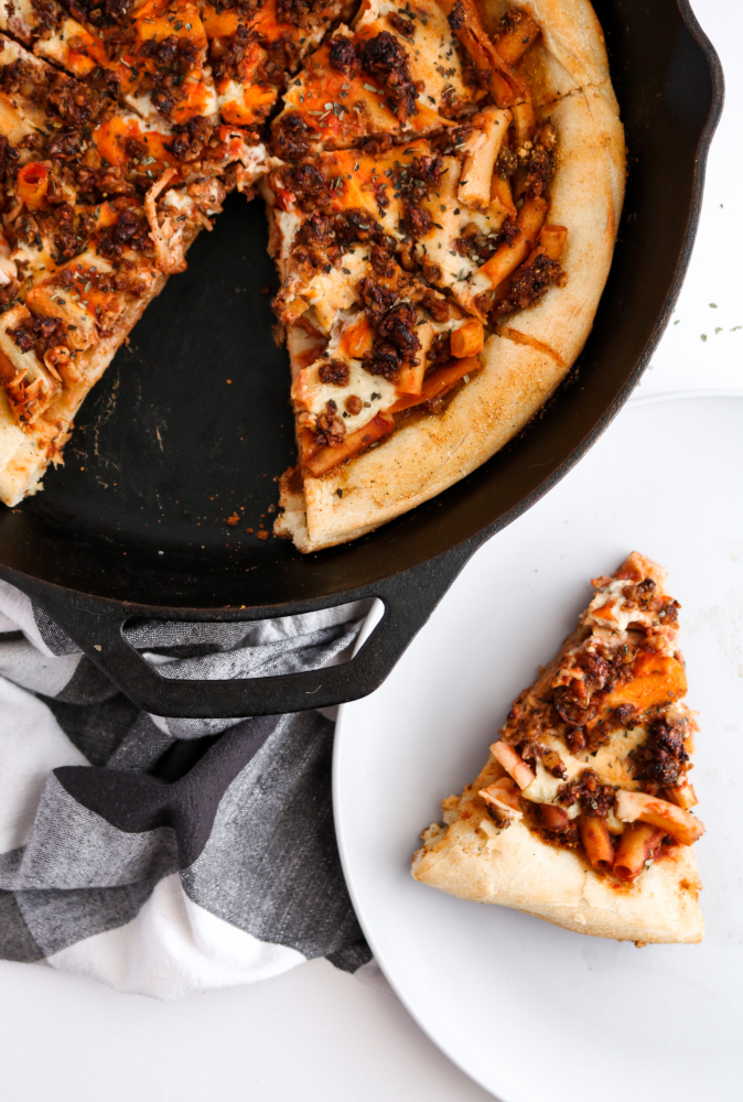 This Vegan Baked Ziti Pizza is like a delicious dream: Saucy chickpea ziti, flavorful walnut sausage, and an ooey gooey mozzarella sauce on a fluffy pizza crust baked to perfection in your cast iron pan. #vegan #vegetarian #pizza #ziti #walnuts // plantpowercouple