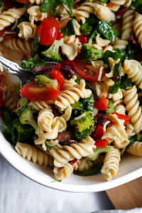 This simple vegan pasta salad recipe is a “grown-up-riff” off the traditional side dish my Gram used to make for me at ALL the family BBQs + parties. It’s quick, easy to make and bursting with flavors of fresh veggies like red peppers, tomatoes, kalamata olives, and more! #vegan #plantbased #recipe #summer #sidedish // plantpowercouple.com