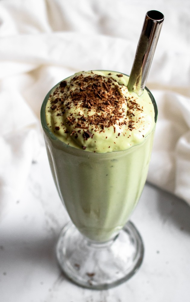 Your favorite childhood St Patrick’s Day treat is now vegan and chock-full of booze thanks to this Boozy Vegan Shamrock Shake recipe! It’s easy to make with a thick indulgent texture that will leave you SHOCKED there’s no dairy in it. #vegan #veganmilkshake #saintpatricksday #avocado #mint #mintchocolatechip #plantbased