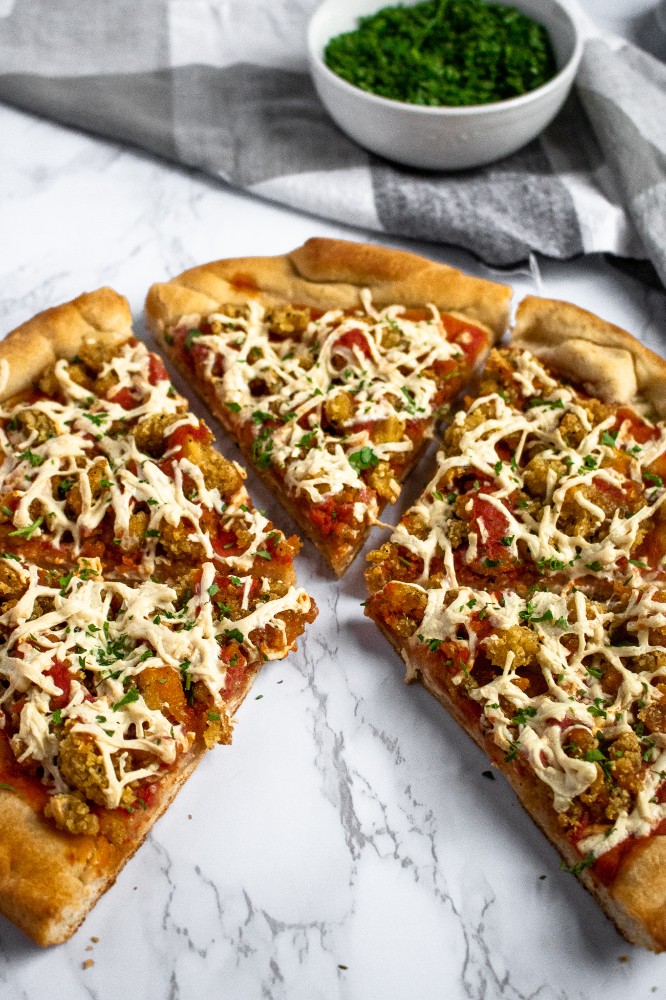 Vegan Chicken Parm Pizza is a fun dinner recipe that’s kid-approved, freezer-friendly, and easy to make. A delicious twist on two classic comfort foods, you can make this vegan pizza from-scratch OR use some of the store-bought shortcuts we suggest. #vegan #plantbased #veganpizza #pizzarecipe #vegancomfortfood #comfortfood #pizza #dinner