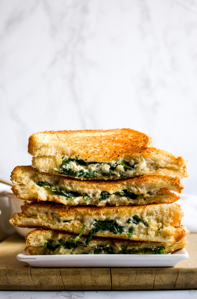 This vegan feta grilled cheese with spinach is our fun take on a classic grilled cheese and pairs perfectly with tomato soup. The easy recipe uses either our homemade tofu feta or one of the many store-bought vegan fetas now available. It will impress the pants off your next lunch guests! #vegan #vegancheese #veganfeta #vegangrilledcheese #dairyfree #grilledcheese #veganlunch #veganrecipe #easyveganrecipe #vegandinner #vegansandwich