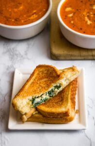 This vegan feta grilled cheese with spinach is our fun take on a classic grilled cheese and pairs perfectly with tomato soup. The easy recipe uses either our homemade tofu feta or one of the many store-bought vegan fetas now available. It will impress the pants off your next lunch guests! #vegan #vegancheese #veganfeta #vegangrilledcheese #dairyfree #grilledcheese #veganlunch #veganrecipe #easyveganrecipe #vegandinner #vegansandwich
