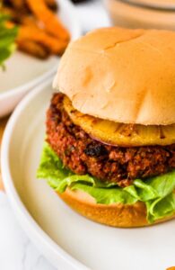 This Hawaiian-inspired vegan teriyaki burger is the meatiest and tastiest on the planet! If you love teriyaki chicken, you’re going to love this plant-based homemade burger! It starts with a blend of TVP and vital wheat gluten with a little beet puree thrown in for a meaty color. Then, it’s flavored with the perfect blend of garlic, ginger, red onion, and teriyaki sauce. It’s topped with a grilled pineapple slice and spicy teriyaki mayo. It’s a great vegetarian option for cookouts and guaranteed to be your new favorite summer veggie burger.