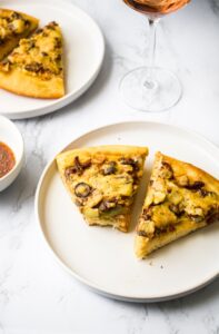 This easy vegan white pizza recipe is impossible to resist! Marinated vegetables like sun-dried tomatoes, garlic, olives, artichokes, and mushrooms are nestled between two layers of thick and creamy dairy-free white sauce. This vegan pizza recipe uses a vegan white sauce that’s made without any vegan cheese, milk, or cashews! It’s a fun and easy option for plant-based pizza night that will seriously impress!