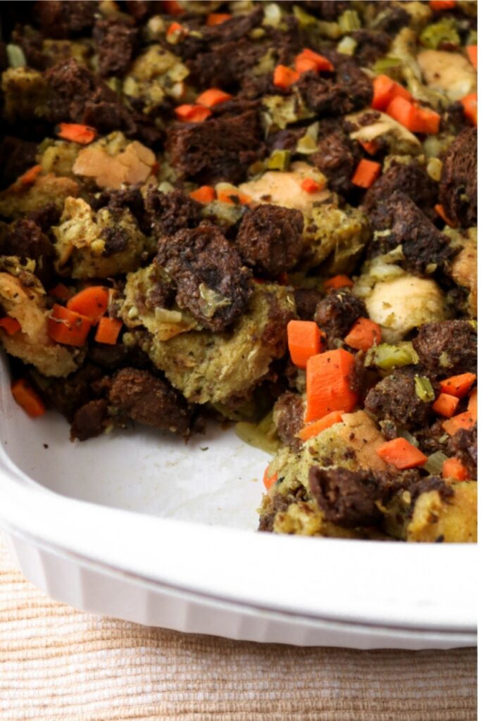 Overhead view of a white rectangular casserole dish filled with vegan stuffing with pumpernickel and sourdough bread