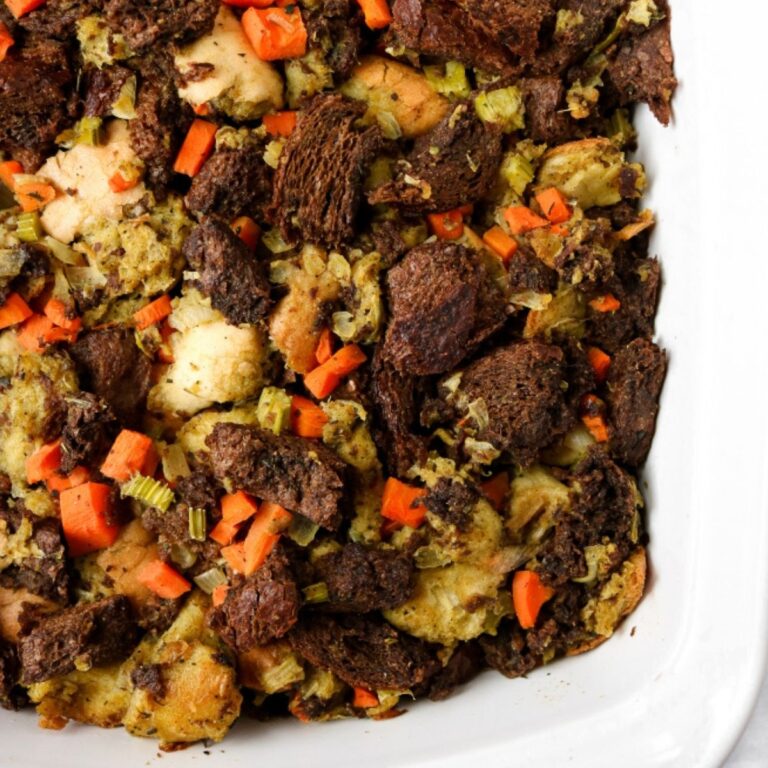 Overhead view of a white rectangular casserole dish filled with vegan stuffing with pumpernickel and sourdough bread