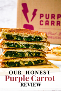 Head on shot of a stack of vegan spinach artichoke grilled cheese sandwiches on a cutting board. There is a Purple Carrot box in the background. Text reads: our honest Purple Carrot review.