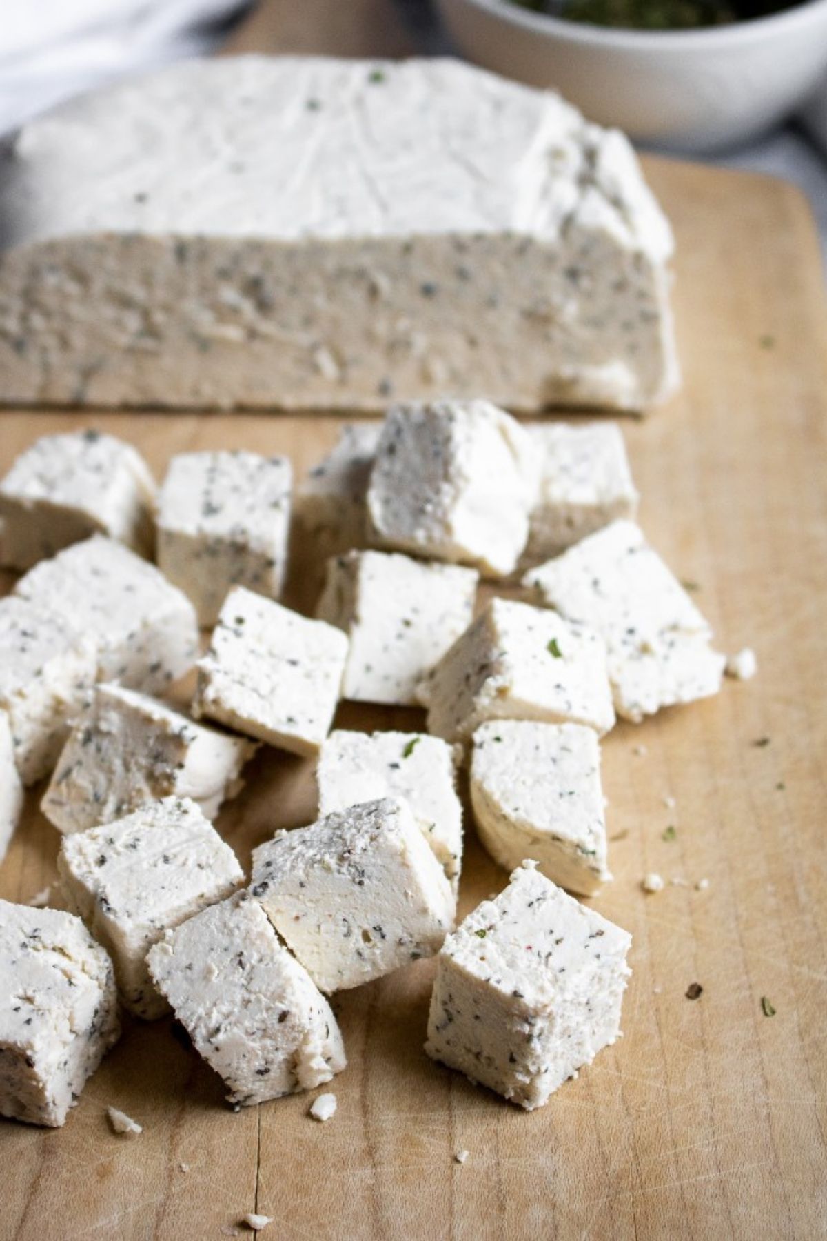 Overhead view of a pile of vegan feta cubes on a wood cutting board