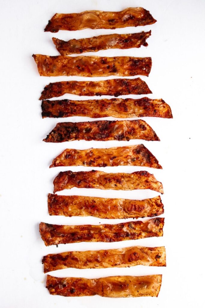 Overhead view of slices of rice paper bacon lying flat on a white background