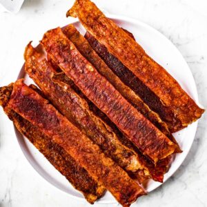 Overhead view of a round white plate with a pile of rice paper bacon on it