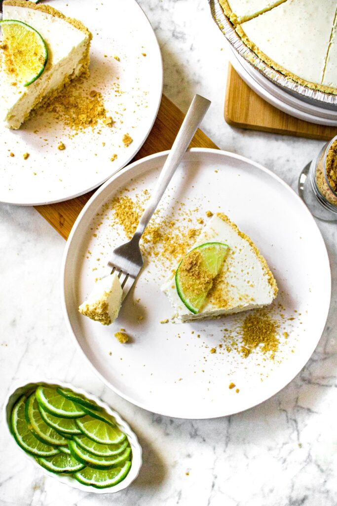Overhead shot of two slices of plant based no bake key lime pie with lime slices and graham cracker crumbs on top.