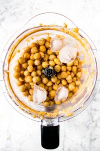 OVerhead shot of a food processor with filled with chickpeas and ice cubes.