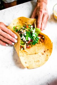 Head on shot of 2 hands wrapping up a healthy mediterranean wrap recipe.