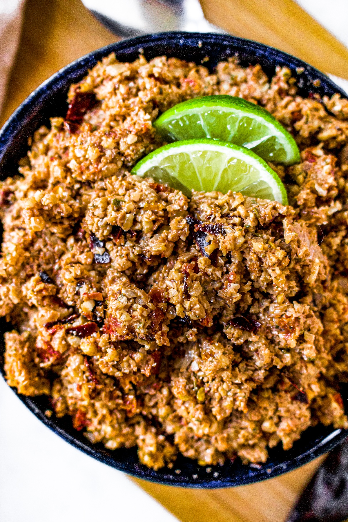 Close up overhead shot of a bowl of vegan ground chorizo with two lime wedges on top