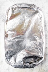 Overhead shot of a rectangular baking dish covered in tin foil