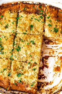 Close up over-head shot of a pan of cooked zucchini lasagna topped with bread crumbs and fresh herbs