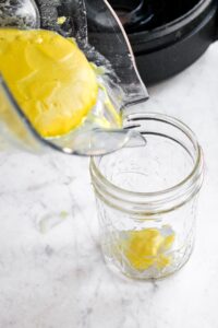 Head on shot of a Vitamix blender pouring homemade vegan cream of chicken into a glass mason jar