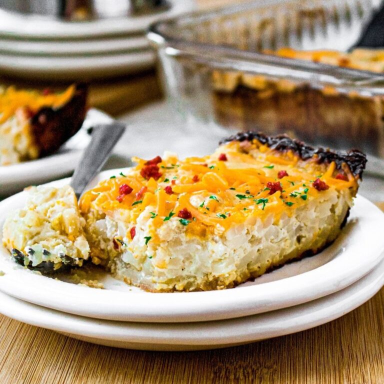 Head on view of a slice of vegan hash brown casserole with a fork next to it that has a bite taken out of the casserole on it