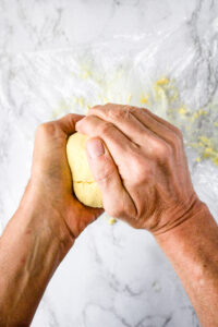 Two hands molding a tofu dairy-free cheeseball