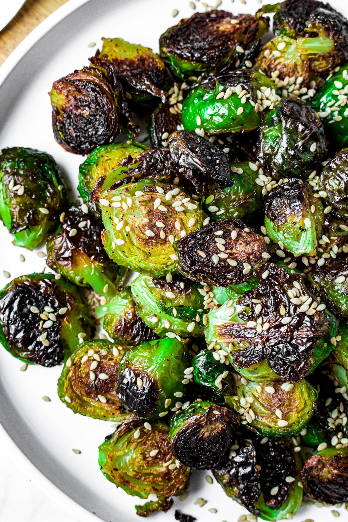 Overhead close up shot of a pile of oven-roasted brussel sprouts sprinkled with white sesame seeds