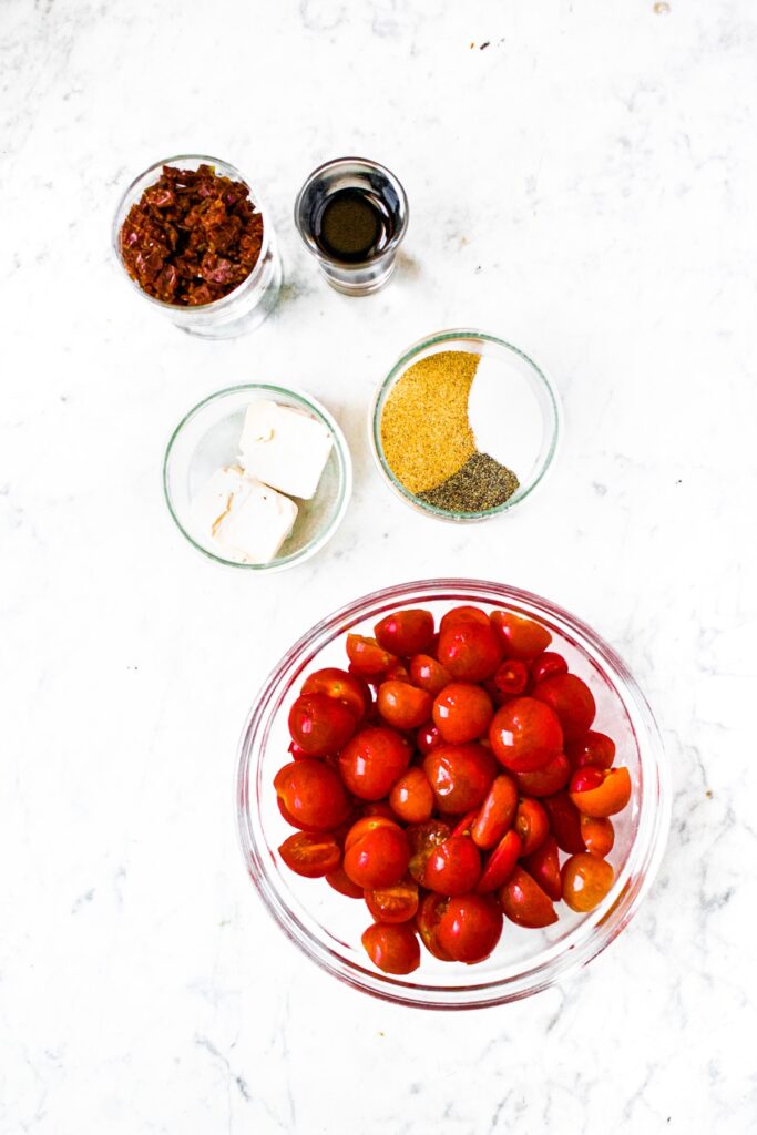 Overhead shot of the ingredients needed to make cherry tomato jam: cherry or grape tomatoes, vegan butter, spices, balsamic vinegar, sun-dried tomatoes