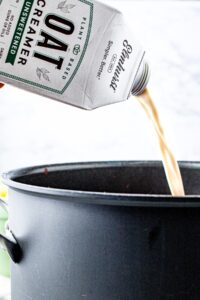 Head on shot of a carton of Elmhurst's unsweetened oat creamer being poured into a pasta sauce pot