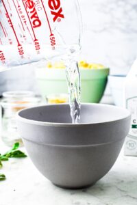 Head-on shot of a mixing cup pouring water into a bowl
