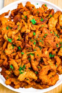 Close up overhead shot of bbq soy curls on a plate with minced parsley on top