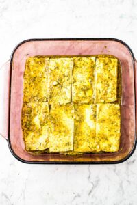 Overhead shot of marinating tofu rectangles in a square glass baking dish