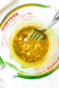 Overhead shot of a garlic soy marinade in a glass measuring cup with a fork sticking into it