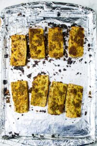 Overhead shot of a foil-lined baking sheet with baked pesto tofu cutlets on it
