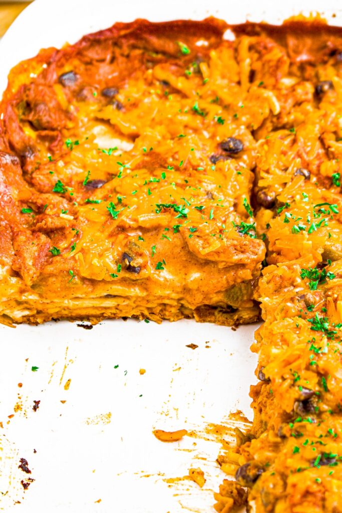 Close up head on photo of a meatless layered enchilada casserole in a large white casserole dish