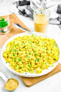 Head on photo of a plate of tofu scramble sprinkled with minced green onions