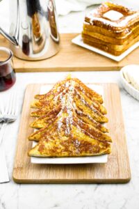 Overhead photo of a plate of sliced French toast with a stack of french toast to the back right corner