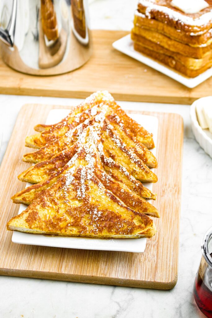 Overhead photo of a plate of sliced vegan french toast with powdered sugar sprinkle and a pot of coffee to the back left corner