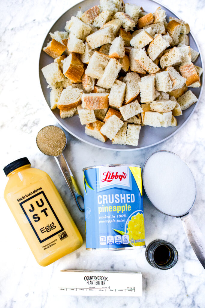 Overhead view of diced baguette on a plate, JUST egg, canned pineapple, country crock plant butter stick, and a Tablespoon of brown sugar