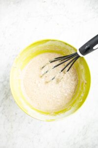 Overhead photo of a healthy whole wheat waffle batter in a bowl with a whisk sticking in it