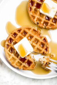 Overhead close up photo of a high-protein waffle topped with vegan butter and maple syrup